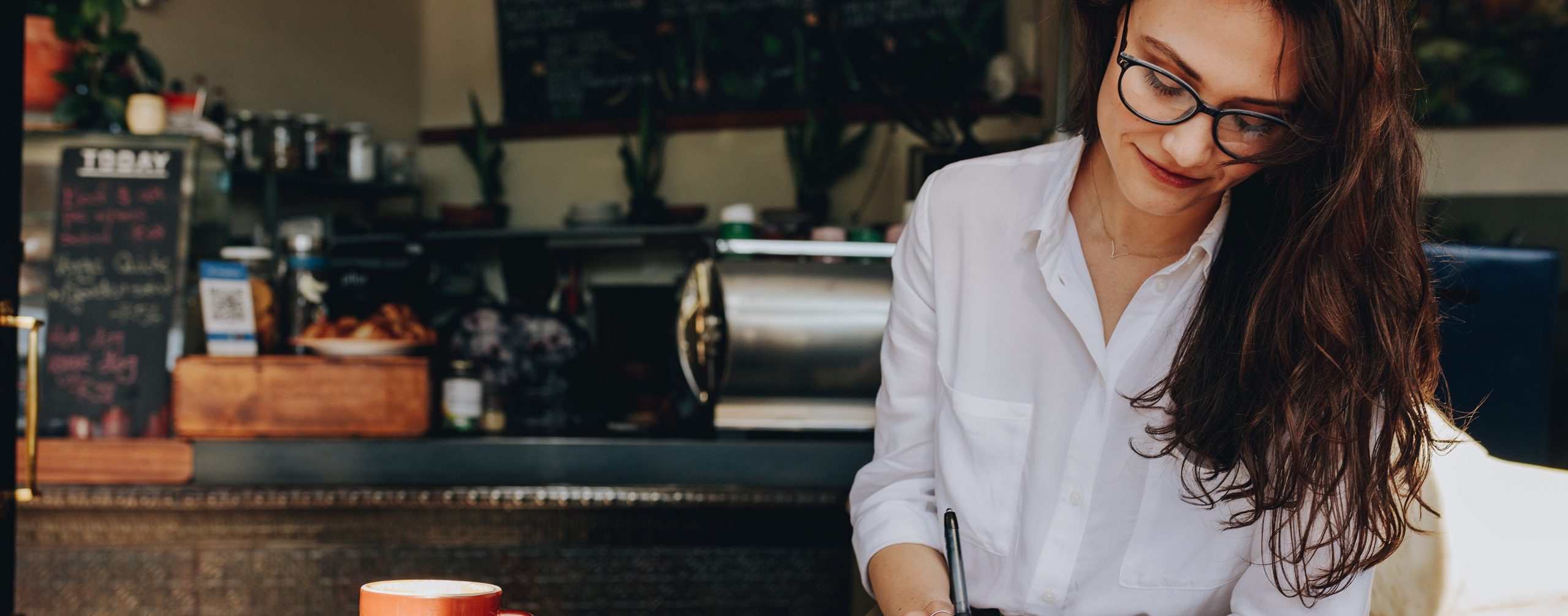 Woman sitting in the cafe writing notes in her diary